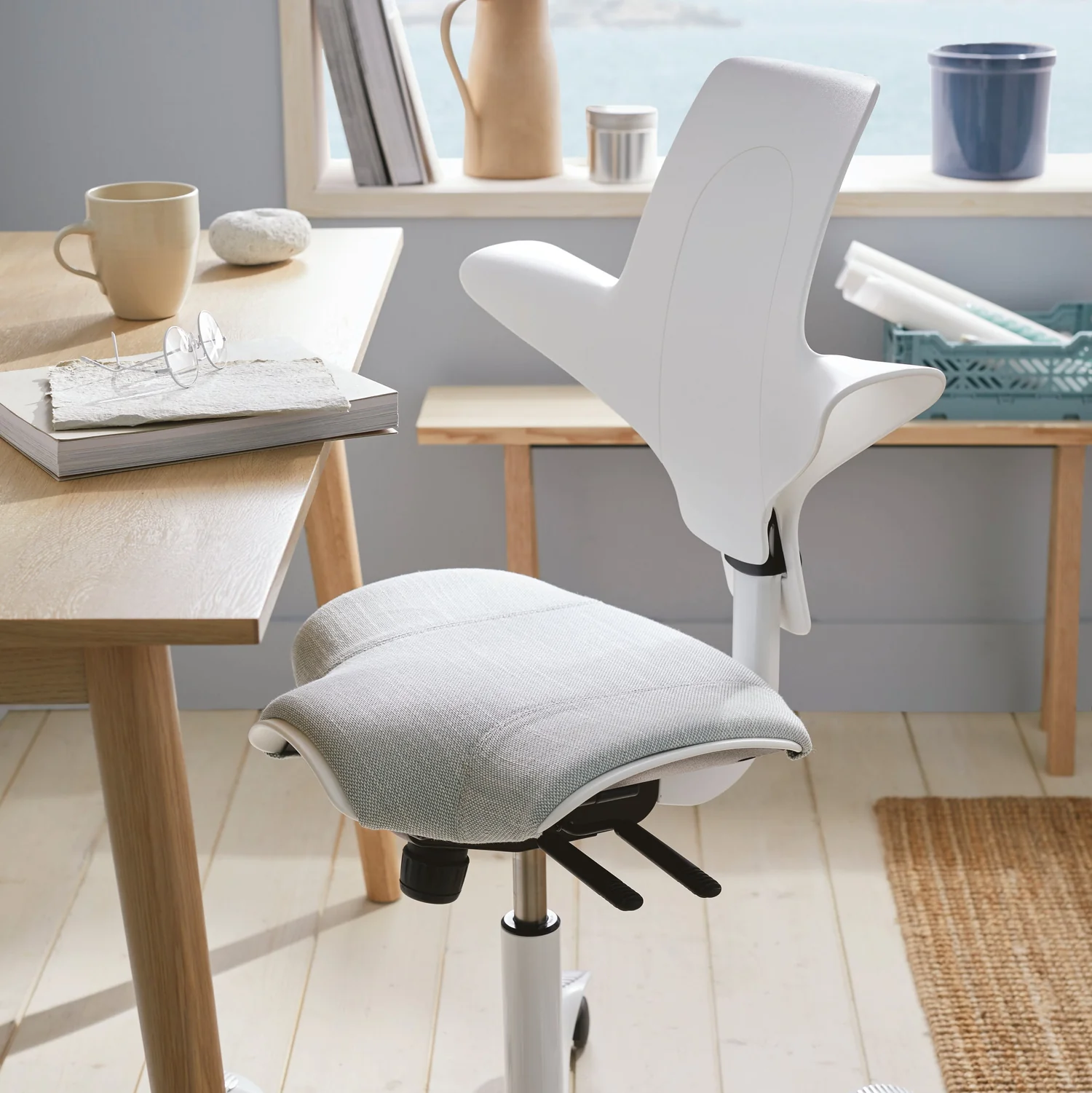 Sitting reversed on the Capisco Puls 8020, chest against the backrest, casual pose